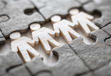 Paper people holding hands in puzzle
